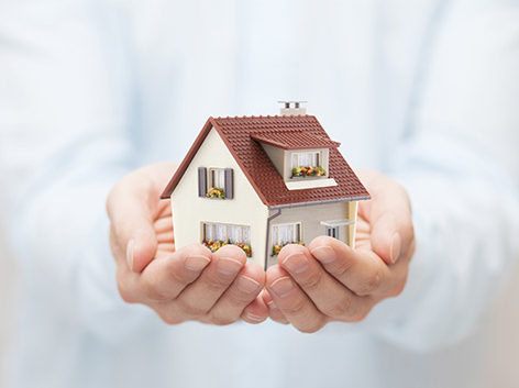IAG Une personne tient une maison en miniature entre ses deux mains